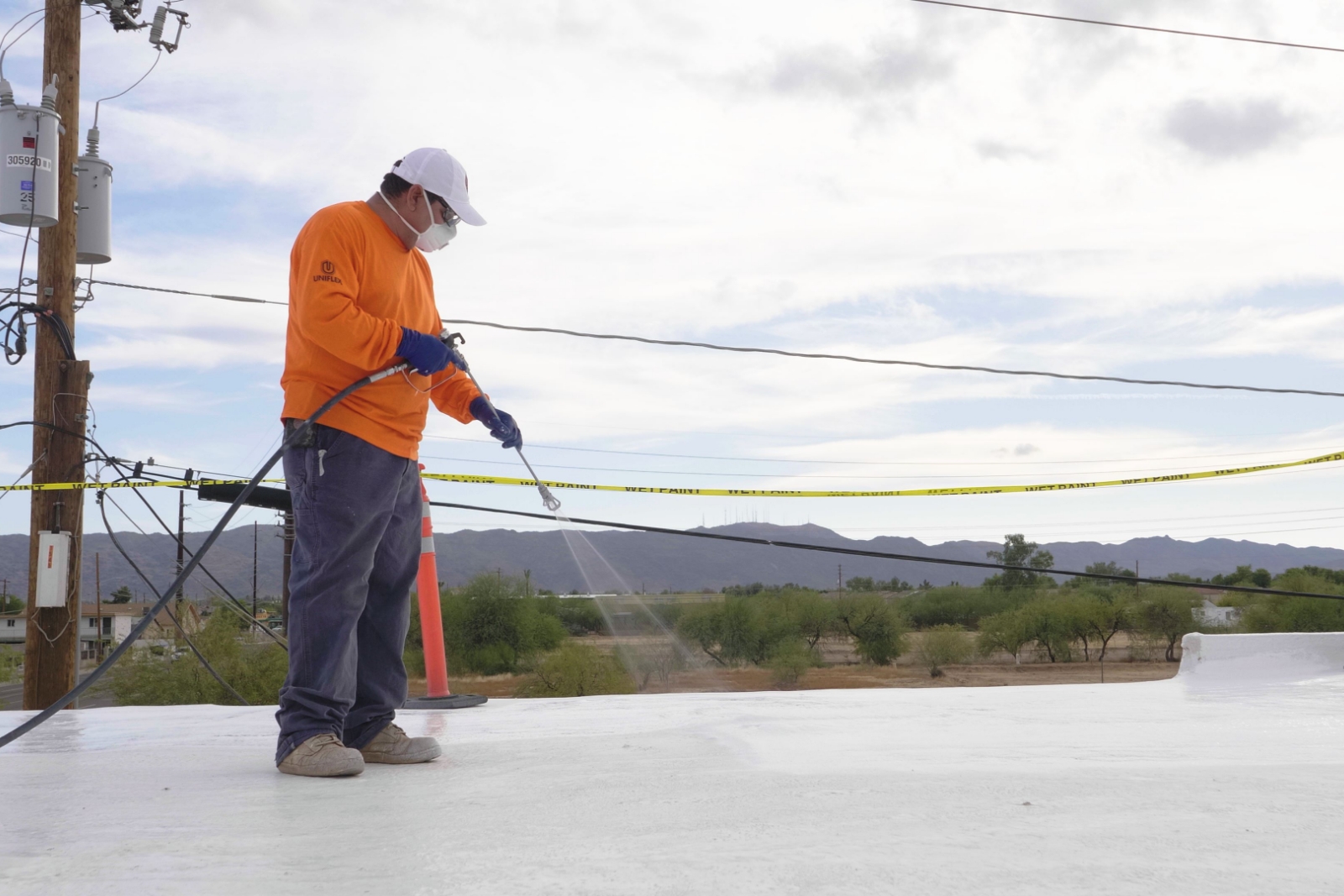 man spraying roof coating