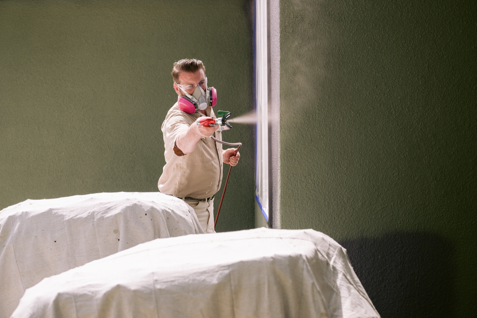 man using paint sprayer inside building