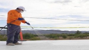 man spraying roof coating