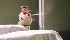 man using paint sprayer inside building