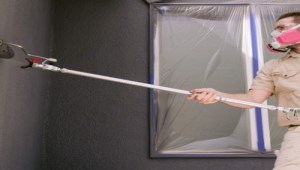 contractor using paint sprayer accessories to paint wall